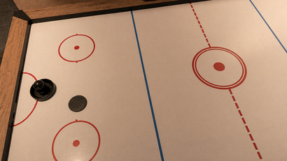 Luft-Hockey-Tisch mit Puck und Schläger auf Spielfeld