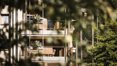 Balkone eines Hauses mit Stühlen und Blumen neben Bäumen