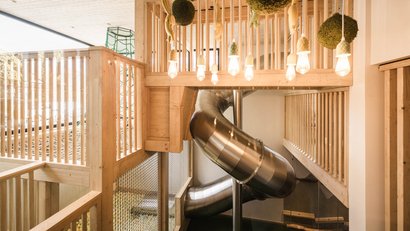 Moderner Innenspielplatz mit Rutsche und Holzgelaendern