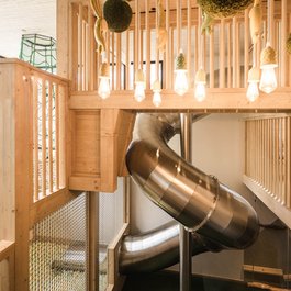 Moderner Innenspielplatz mit Rutsche und Holzgelaendern