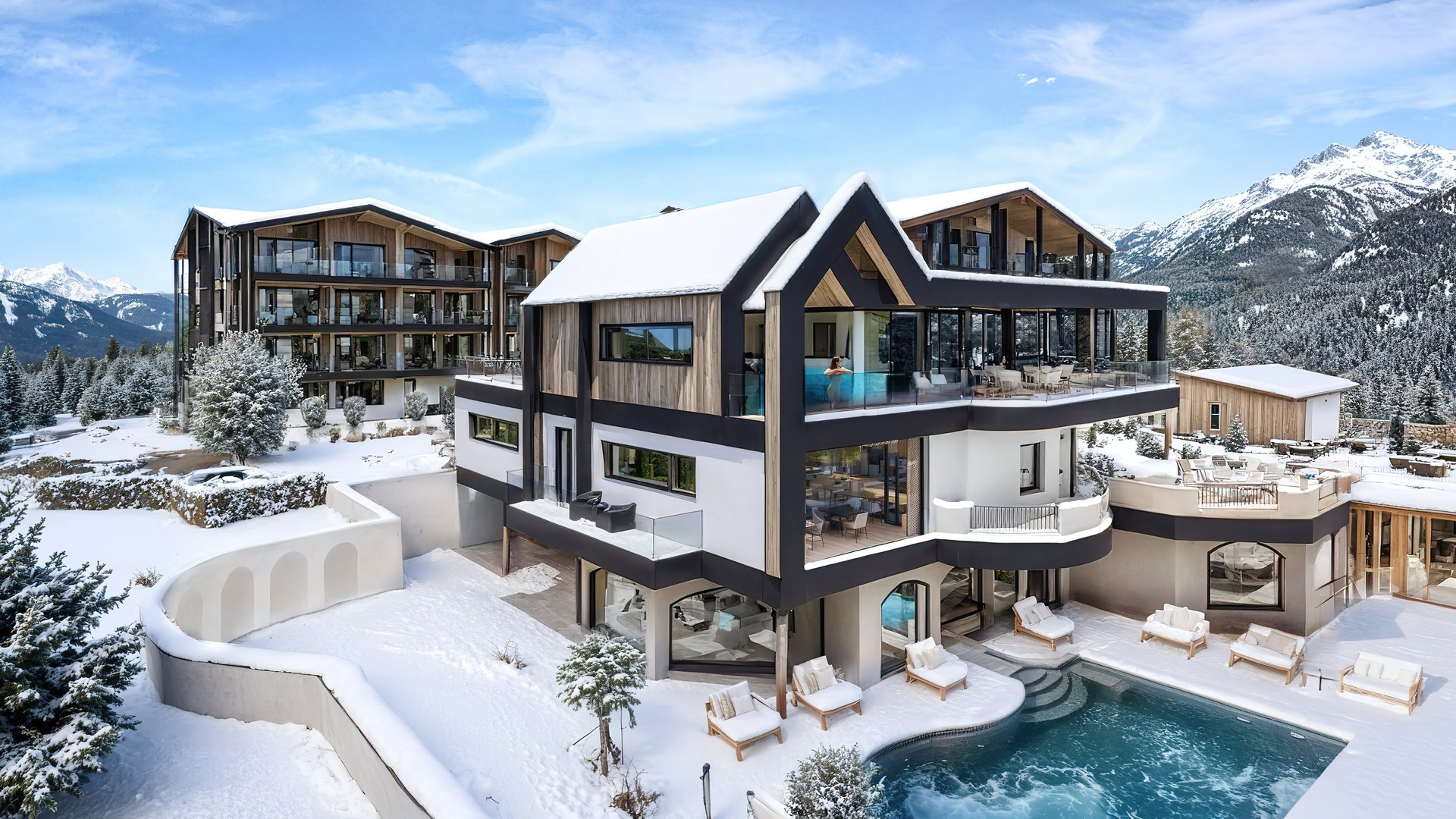 Modernes Chalet mit Pool in verschneiter Berglandschaft unter blauem Himmel