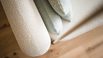 Nahaufnahme eines cremefarbenen Stoffsofas mit Kissen und Holzboden