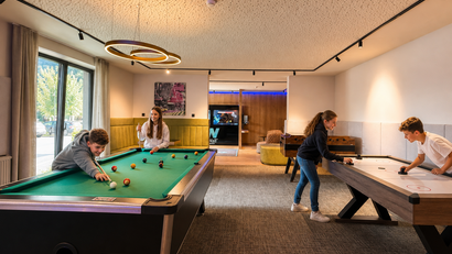 Junge spielen Billard und Airhockey in einem modernen Spielzimmer