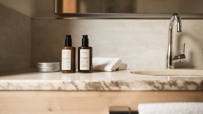 Badwaschbecken mit Lotion und Shampoo Flaschen, Handtüchern und Wasserhahn