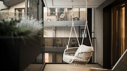 Hängesitz mit Kissen auf modernem Balkon mit Holz und Glas