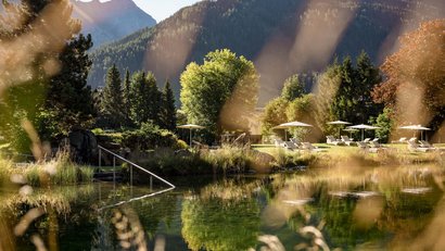 Sonnige Berglandschaft mit Liegestühlen und natürlichem Schwimmteich