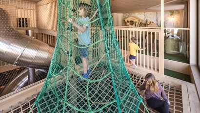 Kinder spielen auf Indoor-Kletternetz und Rutschen im Spielzimmer