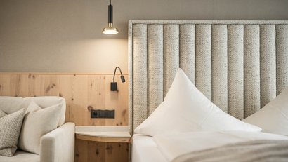 Beleuchtetes Kopfteil und Lampen neben einem gemütlichen Bett und Sofa