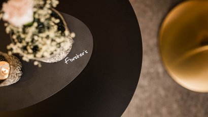 Schwarz runder Tisch mit Vase, Kerze und Forster's Logo