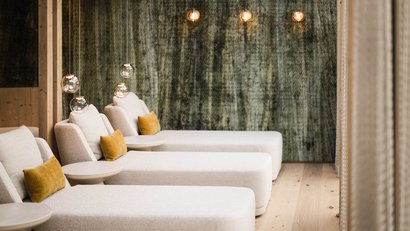 Moderne Lounge mit beigen Sesseln und gelben Kissen vor grauer Wand