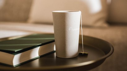 Teetasse und Buch auf einem runden Tisch vor einem Sofa