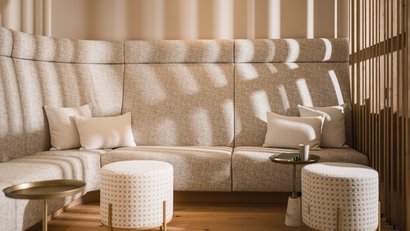 Helles Sitzecke mit beigen Polstern, Kissen und gemusterten Poufs