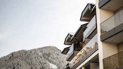 Moderne Balkonfassade eines Gebäudes mit verschneiten Bergen im Hintergrund