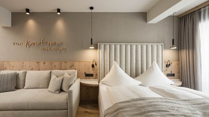 Modernes Schlafzimmer mit Bett, Sofa und natürlicher Holzwandgestaltung